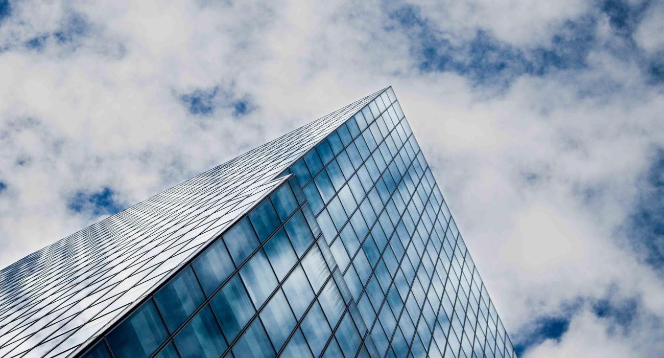 Glass building reflects a cloudy blue sky